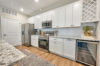 A kitchen with white cabinets and a marble countertop.